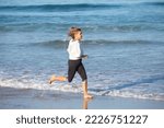 Small photo of Happy senior woman exercising on sea beach on sunny day. Caucasian woman in sports clothes running barefoot in sea water and feeling vivacity. Active lifestyle and sport of elderly people concept