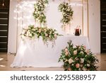 The large bright hall is decorated with flowers for the event, the wedding decor of the presidium table of the newlyweds