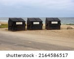 Three large commercial dumpsters rusted with the seawater.