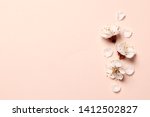 Spring floral background, texture and wallpaper. Flat-lay of white almond blossom flowers and petals over pink background, top view, copy space. Womens day holiday greeting card or wedding invitation
