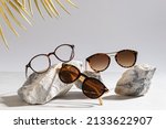 Sunglasses and glasses sale concept. Trendy sunglasses on gray background with golden palm leaves. Trendy Fashion summer accessories. Copy space for text. Summer sale. Optic store discount poster