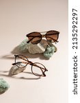 Small photo of Trendy sunglasses and eyeglasses on a beige background. Close up. Sunglasses and spectacles sale concept. Optic shop promotion banner. Eyewear fashion. Minimalism. Vertical