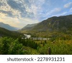 Panorama of a valley between mountains flooded with sun at sunset with the Chuya river flowing under a stone cliff under clouds in the shade in Altai in Russia.