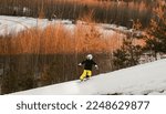Small photo of Logoisk. Belarus. 01.02.2023. A teenage snowboarder descends the slope of a snow-covered mountain in special equipment. Snowboarding - descent at high speed on a special projectile - a snowboard.