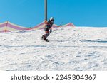 Small photo of Logoisk. Belarus. 01.10.2023. A teenage snowboarder descends the slope of a snow-covered mountain in special equipment. Snowboarding - descent at high speed on a special projectile - a snowboard.