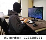 Small photo of Hacker trying to get somebody's password / Programmer with mask (thief) wants to hack your computer