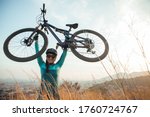 Portrait of female mountain bike on trail. Dressed in blue lifting a double suspension cross country bicycle, xc mtb in the mountain of Collserola in Barcelona