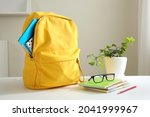 Yellow backpack and stack of notepads on table home. School supplies. Back to school concept. Educational design objects. Home studies.Schoolbag.