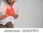 Small photo of Asian young man suffering from central chest pain. Chest pain can be caused by heart attack, myocardial infarct or ischemia, myocarditis, pneumonia, oesophagitis, stress, anxiety, etc,.