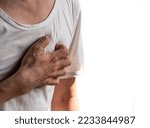 Small photo of Asian young man suffering from left sided chest pain. Chest pain can be caused by heart attack, myocardial infarct or ischemia, myocarditis, pneumonia, stress, etc.