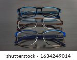 Three different medical eyeglasses for the whole family. Female, male and children's spectacles on a black surface.