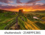 Small photo of Landscape on the Isle of Skye in summer. Sunset over the rocks of Castle Ewen. Colorful sky with clouds. Sun star on the side of the rock. Road and small lake in the background