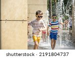 Small photo of Boy having fun in water fountains. Child playing with a city fountain on hot summer day. Happy kids having fun in fountain. Summer weather. Active leisure, lifestyle and vacation.