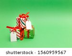 Christmas background with wrapped gifts on green background. Happy holidays creative minimal concept design. Festive seasons greetings card lay out. Christmas presents stacked with blank name tags.
