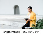 Small photo of Chubby girl sitting on the white stage reading scrip on tablet.