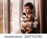A sad boy looks out the window...