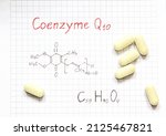 Small photo of Chemical formula of Coenzyme Q10 and some pills on the paper background. Useful vitamin quinone for cells. Close-up.