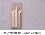 Wooden cutlery, knife, fork, spoon on paper napkin. Simple fabric brown tablecloth on background. Zero waste, wooden utensils, recycling, takeaway, eco friendly, fast food concept. Copy space. Nobody.