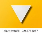 White paper cut into triangle shape, play button set on yellow paper background.