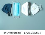 Different protective masks on blue background with copy space. Reusable fabric mask, disposable medical mask, facemask respirator with breathing valve. Right choosing for protection. Virus protection