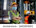Factory woman worker or technician with hygienic mask stand with confident action with her co-worker engineer in workplace during concern about covid pandemic in people affect industrial business.