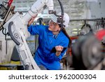 Asian factory worker woman hold tablet and maintenance with check part of robotic machine in workplace area. Industrial and technology support system help in working of employee concept.