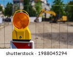Small photo of Construction safety. Street barricade with warning signal lamp on a fence. Blur site background