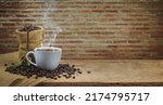 Small photo of A white cup of coffee on wooden table with bric background. Coffee time. Coffee beans.