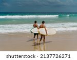 two surfers enter the ocean 