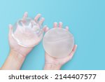 Silicone implant breast augmentation on space blue or turquoise background, Gel type rough and smooth touch surface in two hand, Medical equipment used in clinic or hospital.