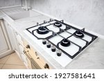 Small photo of Modern white gas stove on counter top closeup. Hob gas stove made of tempered white glass using natural gas or propane for cooking on light countertop with sink faucet mixer tap in kitchen interior.