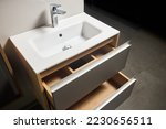 Small photo of Solutions for placing things in bathroom horizontal sliding pull out drawer shelves storage in a cupboard under stoneware washbasin cabinet under sink and faucet. Modern loft flat minimalistic design.