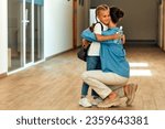 Small photo of Back to school. Mom brought her daughter to school and said goodbye to her in the school corridor. A parent taking a child to school. Education and science concept.