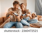 Young couple in love playing video games while sitting on the sofa in the bedroom, having fun and enjoying each other on their weekends.