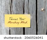 Dry flower on wood background with note written TAME YOUR MONKEY MIND, Buddhism mindfulness practice to control distraction wandering mind which unfocused jumping from thought to thought like monkey 