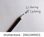 Pencil on white paper with check box HEARING and LISTENING, concept of choose to listen than just hear, pauy more attention and understand meaning behind the words
