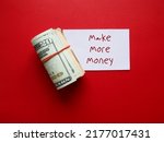 Small photo of On red background, cash dollars money in rubber band with note paper written MAKE MORE MONEY, concept of make more income from side gig or second job to earn extra cash