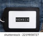 Small photo of Black corporate ID card on jeans background with text label NEWBIE, refers to inexperienced newcomer wirker employee in the workplace,one who has just started doing activity or first jobber