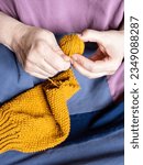 Small photo of front view of women's hands unravel knitted sweater close up