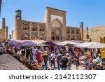Small photo of Central street of city Khiva, Uzbekistan. Traders, tourists, passers-by - scurry back and forth about their business. Building of old madrasah Kutlug-Murad-inak is on background