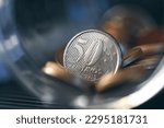 Brazilian coins inside a glass jar. Highlight for 50 cents coin. Brazilian economy. Dark environment. Macro photography.