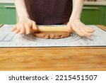 Rolling out gingerbread dough on a silicone baking mat on a wooden table with copy space.