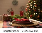 Christmas and New Year 2023, a beautiful setting of the New Year's table in red, against the background of a decorated Christmas tree and a window with a winter landscape
