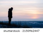 Small photo of Pray. Repentance. Silhouetted men on a background of blue sky and sunset. Kneeling Prayer to God. Glorification. Praising God. A man with his hands up. Worship God