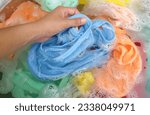 Small photo of woman hand holding a Baby's colorful clothes soaked in soak in powder detergent water dissolution on the cement floor .laundry concept dry and cleaning care for clothes