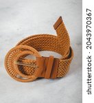 Small photo of Beautiful brown woven belt with round leather buckler over a smoky gray background