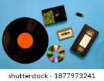 Small photo of A collection of old and modern storage devices technology, Gramophone record videocassette audiocassette tape compact disk hard disk and flash drive on blue background