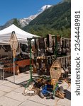 Small photo of Chamonix, Haute-Savoie, Auvergne-Rhone-Alpes, France - 07 27 2023: Old ski equipment and cowbells for sale at the street market with the Aiguilles du Dru mountains in the background in summer