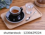 American Espresso Macchiato with Milk and Black Coffee Styled with a Glass of Water, Spoon on a Wooden Serving Tray and Table