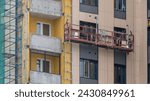 Small photo of Builder making facade of house on lift, Workers on overhead hoist, Hoist in construction of building, Moscow 05 February 2024.